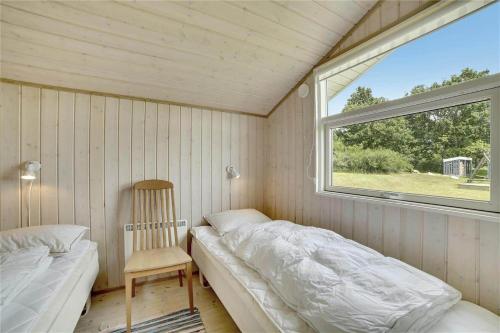 a bedroom with a bed and a chair and a window at 30727-Odder-Alrovej-203-A in Odder