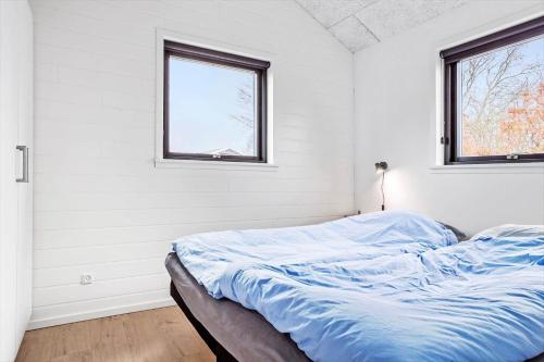 a bed in a white room with two windows at 40149-Juelsminde-Gl-Dykjaer-14 in Juelsminde