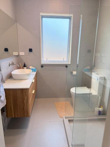 a bathroom with a sink and a toilet and a window at Modern Private 2BR Unit in Takapuna in Auckland