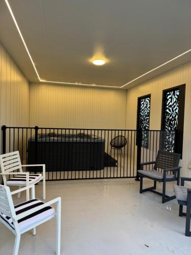 a room with white chairs and a black fence at Coastal Sanctuary, Spa, EV friendly, Pet Firendly with Fireplace, wood provided Just 50m to Kilcunda Beach and 100m to the Ocean View Hotel The Sticks and Copper Door Kitchen Accessibility Friendly in Kilcunda