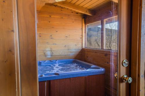 a jacuzzi tub in a cabin with a window at Steps from Pkwy! Hot Tub~Pool Access~Fast WiFi in Pigeon Forge