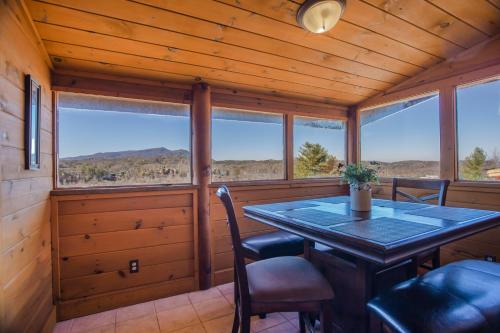 a dining room with a table and chairs and windows at Steps from Pkwy! Hot Tub~Pool Access~Fast WiFi in Pigeon Forge