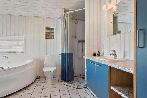 a bathroom with a tub and a toilet and a sink at 40501-Juelsminde-Pot-Strandby-251 in Sønderby
