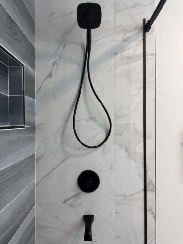 a shower with a black shower head on a marble wall at Sunset Beachside Getaway, 6 mins WALK to the Beach in Panama City Beach