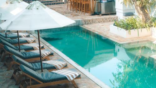 a swimming pool with lounge chairs and an umbrella at Terra Resort in Ahangama