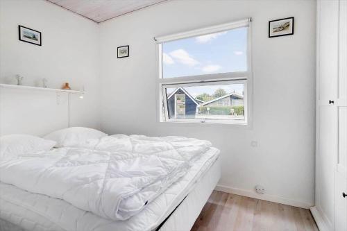 a white bedroom with a bed and a window at 40606-Juelsminde-Pilevaenget-24 in Juelsminde