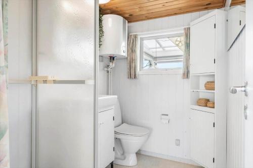 a white bathroom with a toilet and a window at 40606-Juelsminde-Pilevaenget-24 in Juelsminde