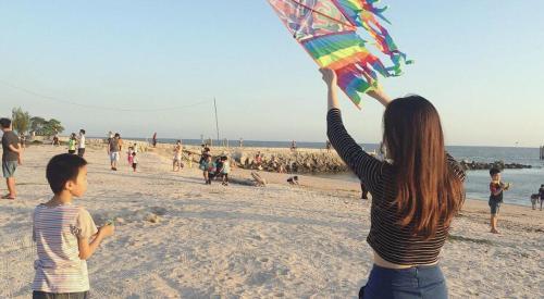 a woman holding a kite on the beach at Shuang Yang Sekinchan Homestay in Sekincan
