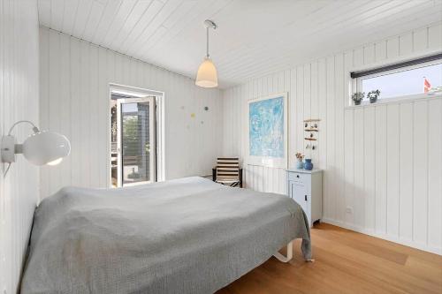 a white bedroom with a bed and a window at 40171-Juelsminde-Poppelalle-29 in Juelsminde