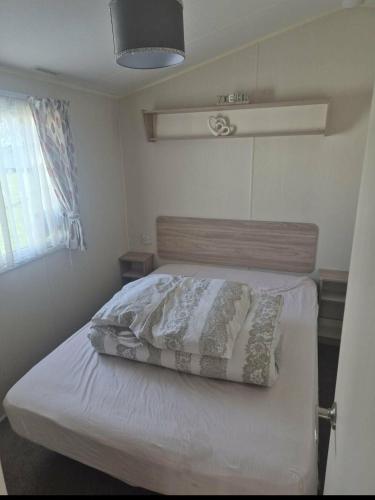 a bedroom with a bed with white sheets and pillows at 3 bed Caravan wink ups towyn in Kinmel Bay