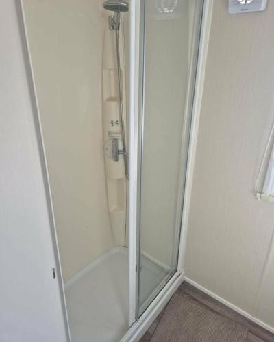 a shower with a glass door in a bathroom at 3 bed Caravan wink ups towyn in Kinmel Bay