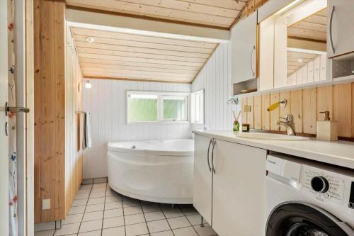 a bathroom with a tub and a sink and a washing machine at 30415-Odder-Strandparksvej-50 in Odder