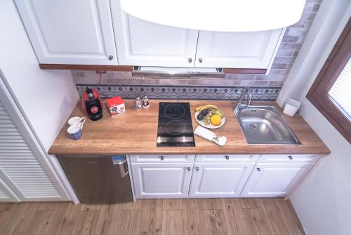 a small kitchen with white cabinets and a sink at Aparthotel Ano in Acharavi