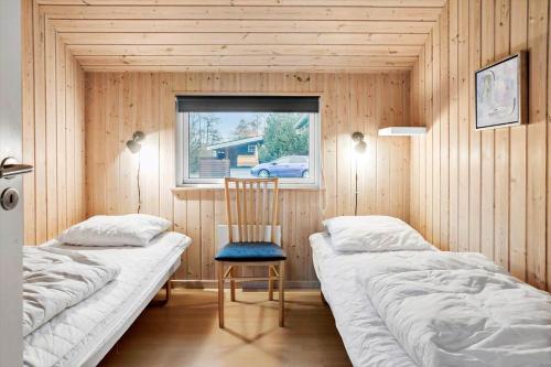 a room with two beds and a chair and a window at M235-Vaeggerlose-Kaninstien-33 in Bøtø By