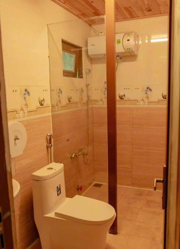 a bathroom with a toilet and a shower at Đồi Lát Homestay in Da Lat
