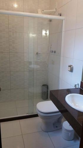 a bathroom with a shower and a toilet and a sink at Pousada Normandy in São Lourenço