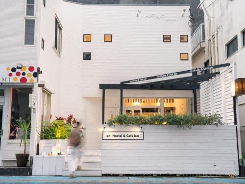 a man walking down a street in front of a building at En- Hostel & Café bar in Amami