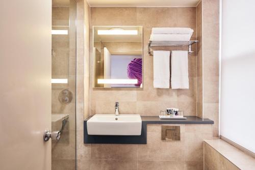 a bathroom with a sink and a mirror and towels at Mercure Exeter Rougemont Hotel in Exeter