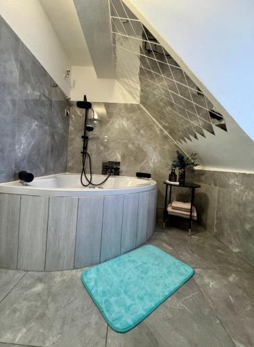 a large bathroom with a tub and a blue rug at Phöenixpalace Whirlpool & Infarotsauna in Dortmund