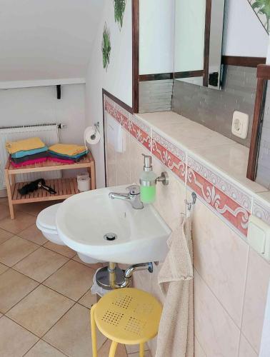 a bathroom with a white sink and a yellow stool at FeWo Hoffmann DG - Ihr Domizil für Arbeit oder Kurzurlaub in Böhlen