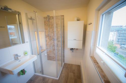 ein Bad mit einer Dusche, einem Waschbecken und einem Fenster in der Unterkunft Ferienwohnung "Beim Nachtwächter" in Görlitz