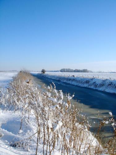 a river with snow on the side of it at Nordsee Haus An't Oll Deep in Dornumersiel