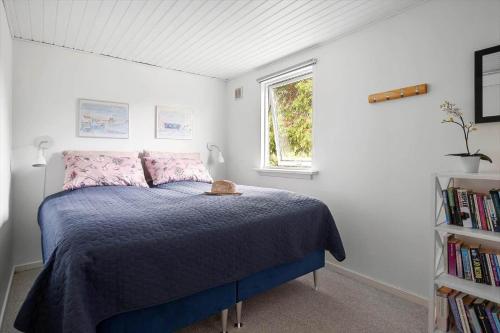 a bedroom with a bed with a blue comforter and a window at 1484-N-Gilleleje-Markvaenget-11 in Gilleleje