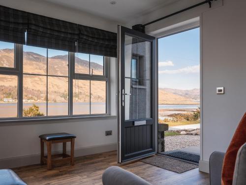 a living room with a door with a view of the mountains at An Dobhran - Ukc5752 in Dornie