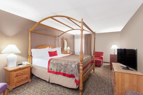 a hotel room with a bed and a flat screen tv at Ramada by Wyndham Fresno North in Fresno