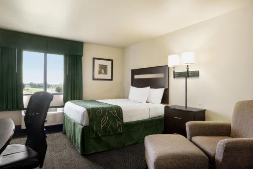 a hotel room with a bed and a chair at Baymont by Wyndham Glenwood in Glenwood