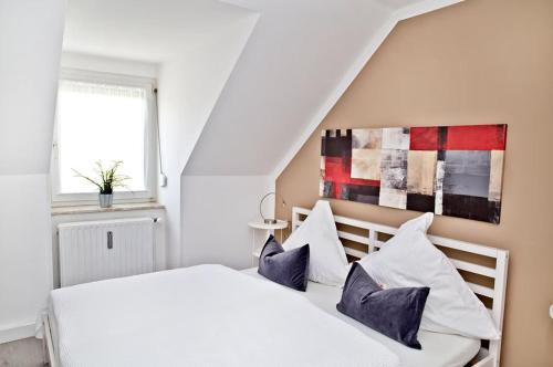 a bedroom with a white bed with blue pillows at Steinhauser`s Ferienwohnungen in Augsburg