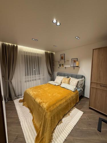 a bedroom with a bed with a yellow blanket on it at Cozy Stay Marijampolė in Marijampolė