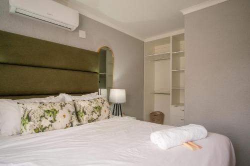 a bedroom with a white bed with a green headboard at Unit 4 at Homely Escapes in Phalaborwa