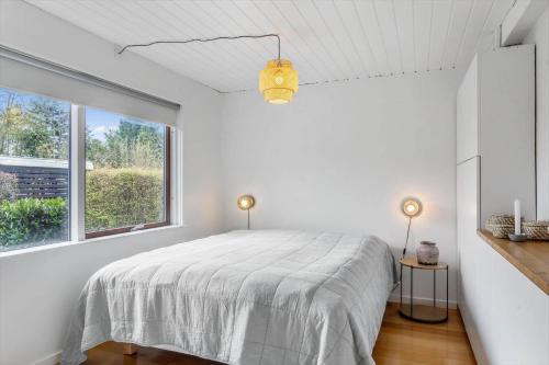 a white bedroom with a bed and a window at 1566-Dronningmolle-Vipstjertvej-12 in Dronningmølle
