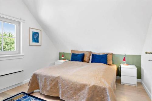 a bedroom with a bed with blue pillows and a window at 1602-Vejby-Brondsholmvej-33 in Vejby
