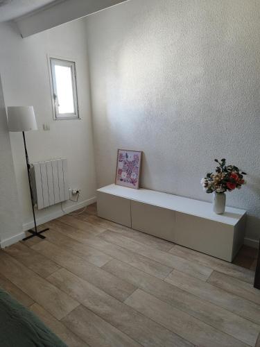 a white room with a bench and a vase of flowers at Appartement en résidence Valras-Plage in Valras-Plage