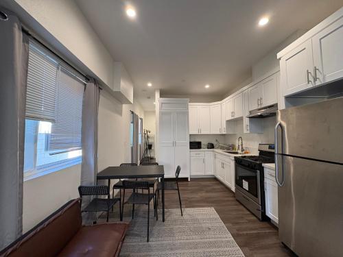 a kitchen with white cabinets and a table and chairs at Blue Central Stay Near USC, BMO Stadium & Downtown LA in Los Angeles