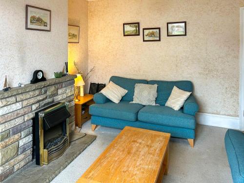 a living room with a blue couch and a fireplace at The Castaway in Mundesley