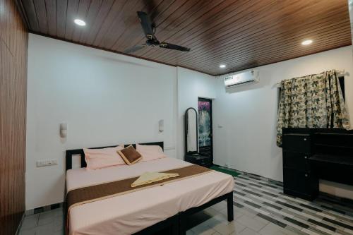 a bedroom with a bed and a ceiling fan at Marari Jackson Beach Homestay in Mararikulam