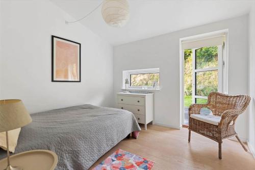 a bedroom with a bed and a chair and a window at 823-Tisvildeleje-Vibevaenget-13-A in Tisvildeleje