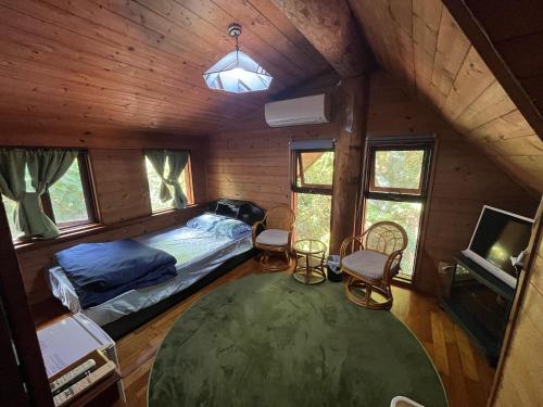 a bedroom with a bed and chairs in a cabin at PrivateVillaHutamiLog in Nago