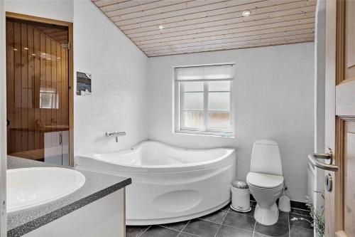 a white bathroom with a tub and a toilet at 30859-Ulfborg-Bellisvej-432 in Ulfborg