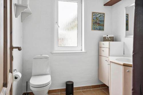 a bathroom with a toilet and a sink and a window at 70099-Ulfborg-Klitrosevej-2 in Ulfborg