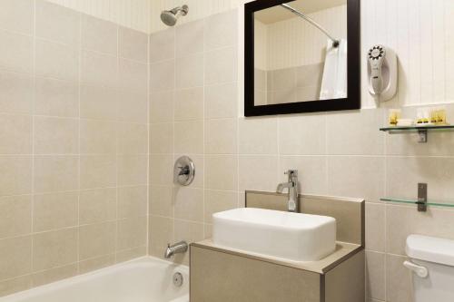 a bathroom with a sink and a tub and a mirror at Days Inn by Wyndham Vermilion in Vermilion
