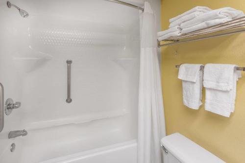 a bathroom with a tub and a shower with towels at Baymont by Wyndham Fayetteville in Fayetteville