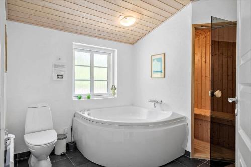 a white bathroom with a tub and a toilet at 10706-Ulfborg-Graevlingevej-3 in Ulfborg