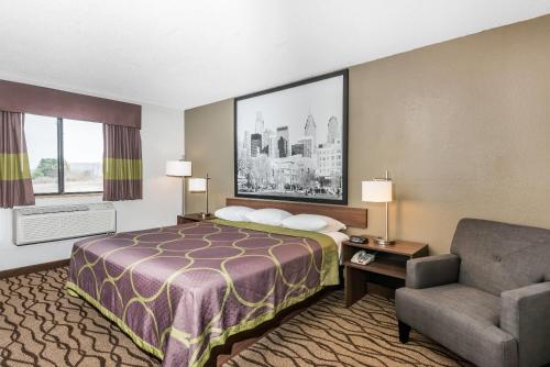 a hotel room with a bed and a chair at Super 8 by Wyndham Bedford in Bedford