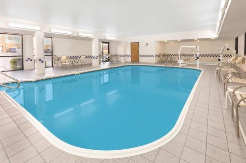 a large pool in a hotel with chairs and tables at Baymont by Wyndham Oklahoma City/Quail Springs in Oklahoma City
