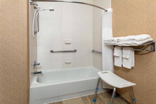 a bathroom with a tub and a shower with a stool at Baymont by Wyndham Oklahoma City/Quail Springs in Oklahoma City