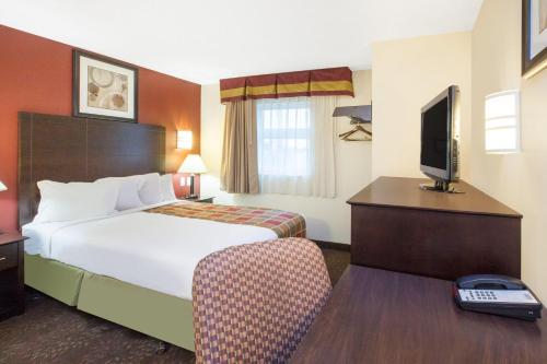 a hotel room with a bed and a television at Travelodge by Wyndham Romulus Detroit Airport in Romulus